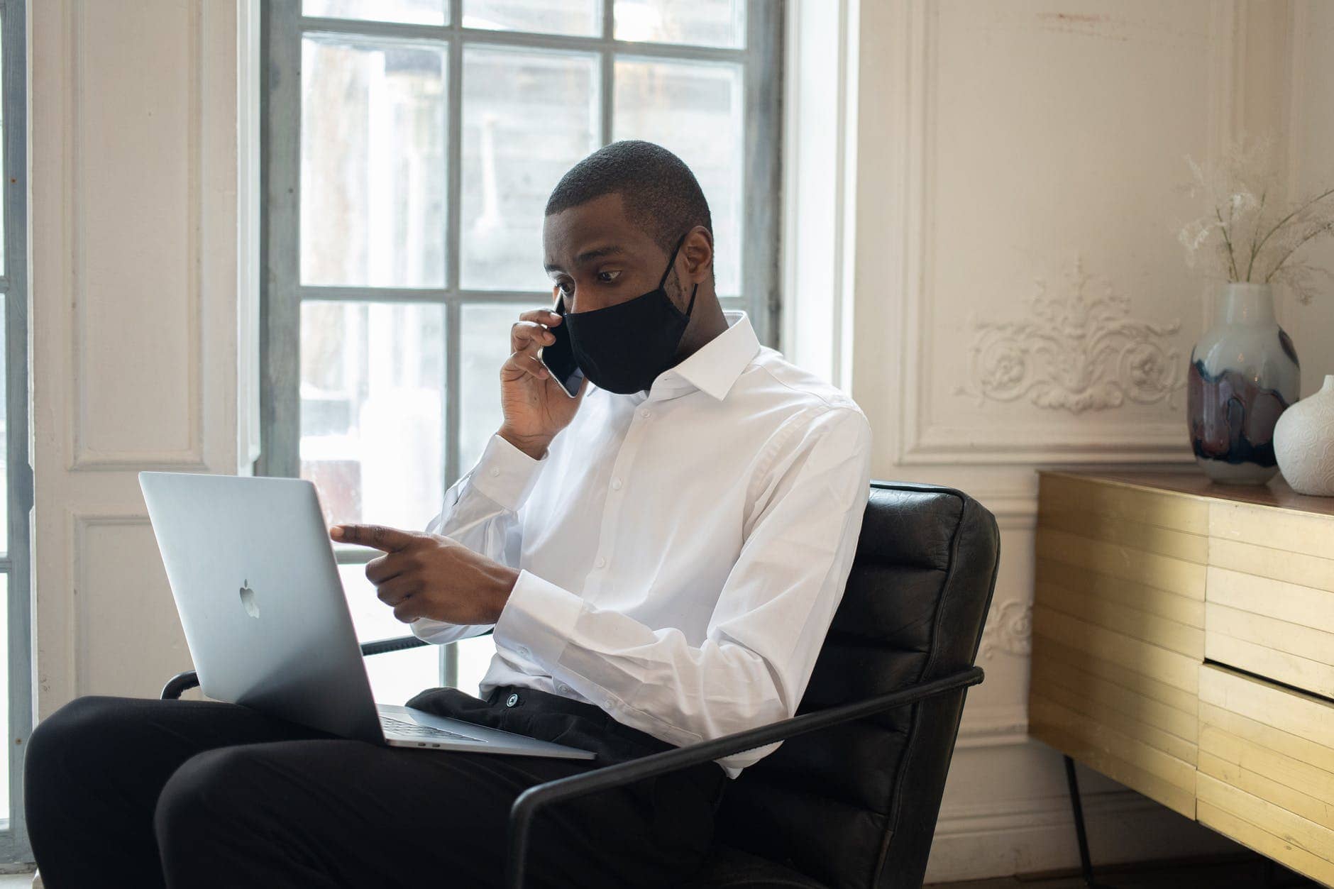 privacy policy black businessman in mask using laptop while talking on smartphone